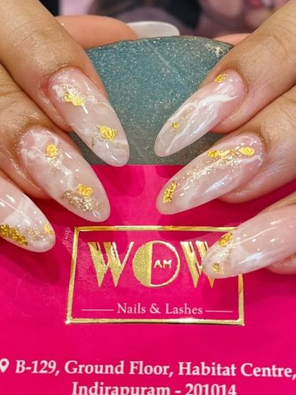 This elegant design on long, almond-shaped extensions features a milky white marble effect with delicate flakes of gold foil. It's a luxurious and sophisticated choice.