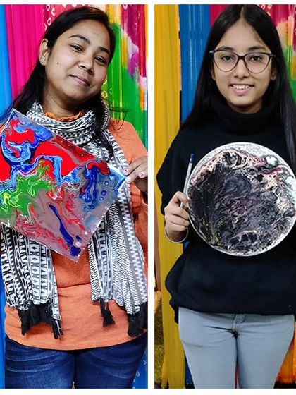 Two students showcasing their unique fluid art creations. Notice how the same technique can result in vastly different but equally beautiful abstract designs.