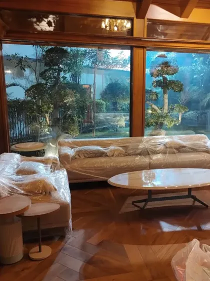 The living area of the gazebo, still wrapped for protection, looks out onto the beautifully landscaped garden. The design ensures a constant connection with nature.