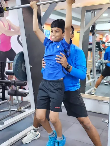 Even our youngest players are introduced to strength training with proper guidance, like this assisted pull-up to build upper body strength.
