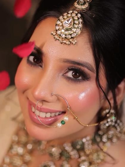 A joyful close-up of the bride, with rose petals falling around her. Her glowing cheeks and bright smile capture the happiness of the moment, enhanced by a radiant makeup look.