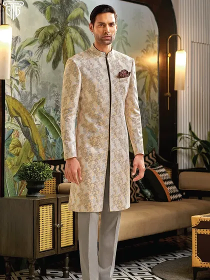 This elegant sherwani in a light jacquard fabric features a subtle black trim for a touch of modern contrast. It is a sophisticated choice for a day wedding or a grand celebration.