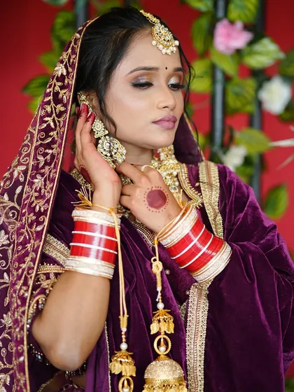 A candid pose showing the intricate details of the bride's jewelry and the beautiful henna on her hands. The smoky eye makeup adds a touch of modern glamour to the look.