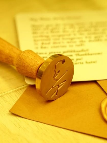 The custom wax seal stamp and a sealed envelope, a small but significant detail that adds a touch of old-world elegance to the wedding favors.