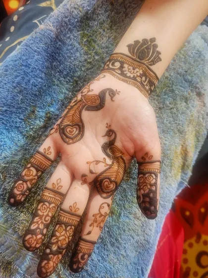 A playful design with two small peacocks on the palm, complete with heart details. The wrist cuff features a simple lotus design.