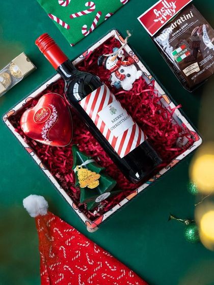 The 'Jolly Feast' hamper being assembled, with red crinkle paper adding a pop of festive color.