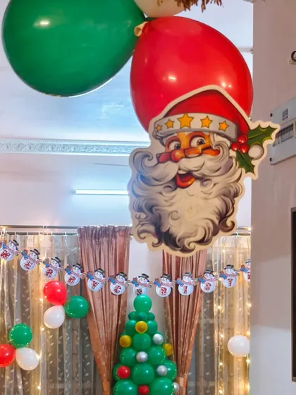 Details matter in our decorations. This close-up shows a classic Santa Claus cutout and festive red and green balloons we used as part of a complete home Christmas decor package.