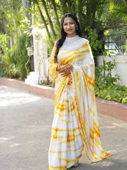 A classic and elegant Haldi look. The bride wears a beautiful tie-dye saree with a pearl-embellished blouse, paired with minimal makeup.