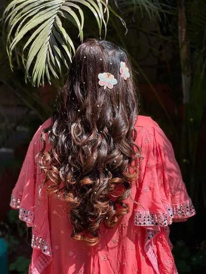This hairstyle looks stunning in the sunlight. The pearls catch the light beautifully, and the soft curls are perfect for an outdoor mehendi or haldi event.