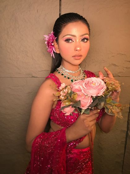 'Rosemary' is a fresh and pretty look. The model wears a sparkling pink saree with a flower in her hair, and the makeup is soft and glowing.