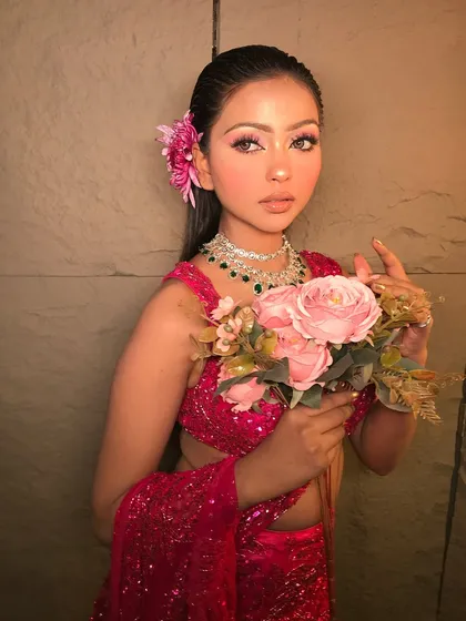'Rosemary' is a fresh and pretty look. The model wears a sparkling pink saree with a flower in her hair, and the makeup is soft and glowing.