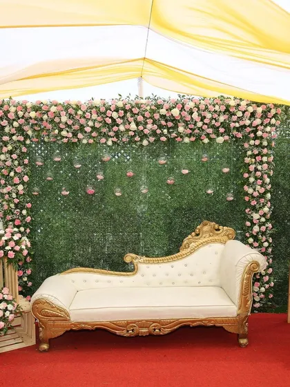 We specialize in creating beautiful settings for intimate events. This photo booth setup for a lockdown wedding features a lush green wall, a cascade of pink and white roses, and a classic chaise lounge for perfect pictures.