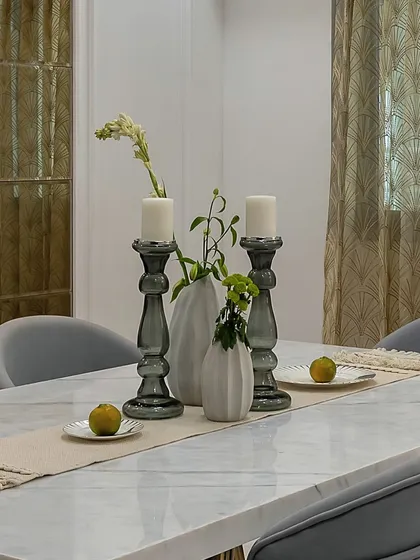 A simple yet elegant tablescape. Smoked glass candle holders and minimalist vases create a beautiful centerpiece on this marble dining table, proving that less can be more.