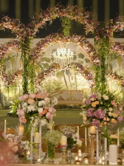 A stage where dreams unfold. This setup combined lush floral arches, cascading greens, and a crystal chandelier to create a scene of timeless elegance and modern romance.