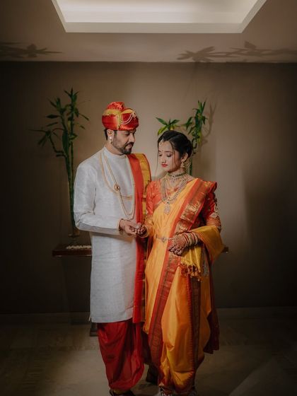 A full-length indoor portrait of the couple, showcasing the elegant drape of the bride's navari saree and the groom's classic sherwani.