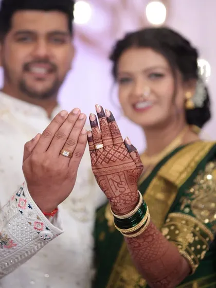 A happy couple showing their engagement rings. The bride's rich mehendi stain is a beautiful backdrop for this special moment.