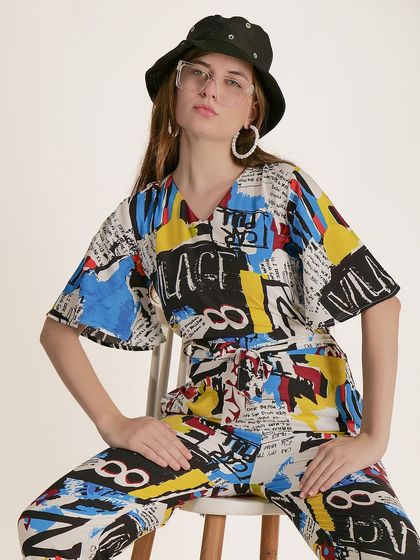 A seated, more composed pose in the same jumpsuit, providing a clear view of the garment's print and fit.
