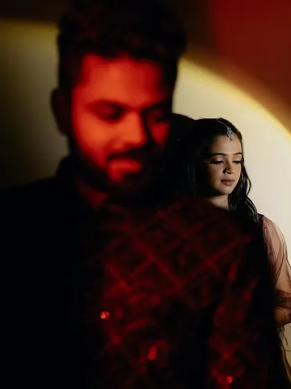 A creative portrait using a spotlight and red gel to create a cinematic, high-contrast look. The focus on the bride while the groom is in silhouette adds a layer of artistic storytelling.