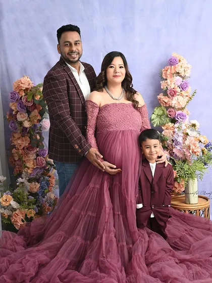 A picture-perfect family portrait. The coordinating mauve and burgundy outfits and the pastel floral background create a rich and harmonious image.