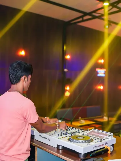 A view from the back, showing me working the decks under the warm yellow lights of the club.