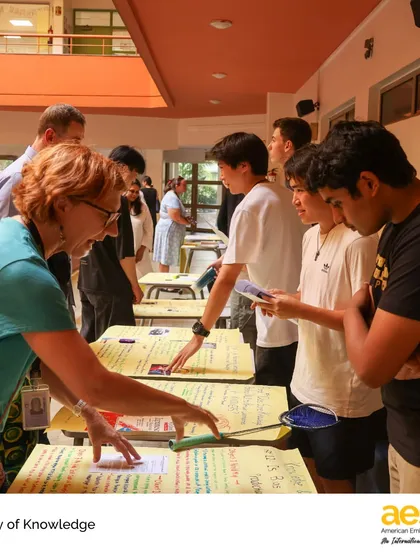 A teacher engages with students at their TOK exhibition booth. Our faculty work closely with students throughout this process, providing guidance and challenging them to deepen their understanding.