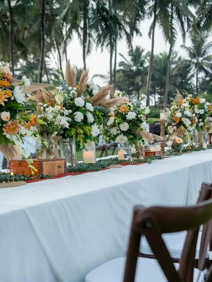A long table setup for a rustic-boho dinner in Goa, with a runner of pampas grass and wildflowers.