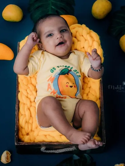 Lounging in a basket of mangoes. This overhead shot shows the full, colorful setup of this fun and fruity 4-month milestone session.