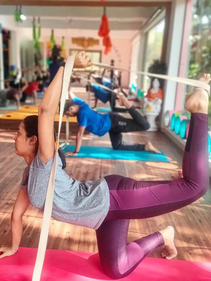 A strap is used here to assist in a standing quadriceps stretch, helping to improve balance and flexibility.