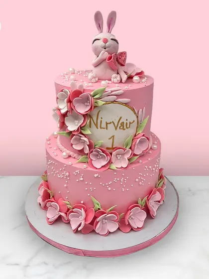A lovely two-tiered pink cake for Nirvair's first birthday, decorated with a cascade of pink flowers and topped with a cute bunny.