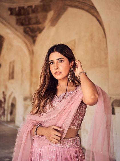 A confident and engaging portrait. The model's direct look and the beautiful backdrop of ancient archways create a compelling image for a modern ethnic wear brand.