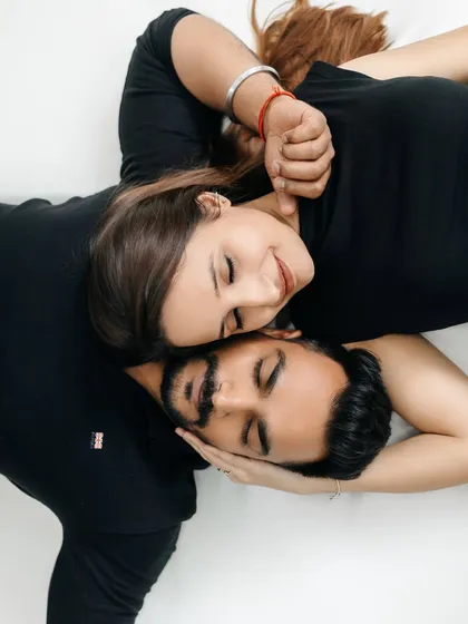 This overhead portrait from a minimalist indoor session highlights the couple's closeness. Shot against a simple white backdrop, the focus is entirely on their serene expressions and intimate connection, creating a timeless and artistic piece of their love story.