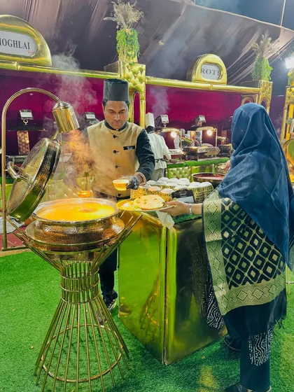 A guest being served at our live Mughlai food station. The steam rising from the golden serving pot creates an appetizing and inviting scene.