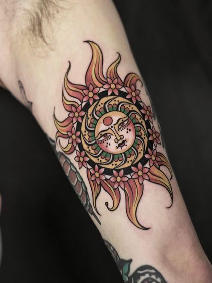 This traditional-inspired sun tattoo glows with warmth and meaning. The use of bold outlines and a classic color palette of reds, yellows, and greens gives this piece a timeless, ornamental quality.