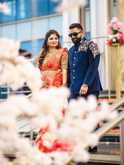 A classic walking shot of the couple, framed by white blossoms for a romantic pre-wedding portrait.