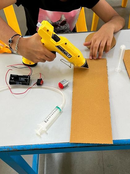 Another angle of a student using a hot glue gun, showing the concentration and care they put into their projects.