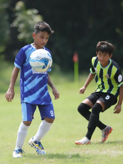 Manas Raj showing great ball control, chesting the ball down under pressure from a defender in a league match.