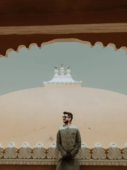 A majestic portrait of the groom. Posed against the backdrop of the palace domes, this shot is framed by a traditional archway, creating a regal and powerful image.