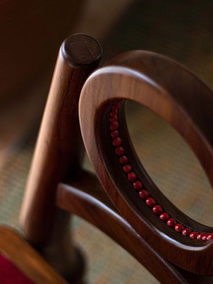 A series of images detailing the Manjadi chair, from its hand-turned legs inspired by the seed pod to the vibrant red upholstery. These shots highlight the craftsmanship and the deep cultural narrative behind this unique design.