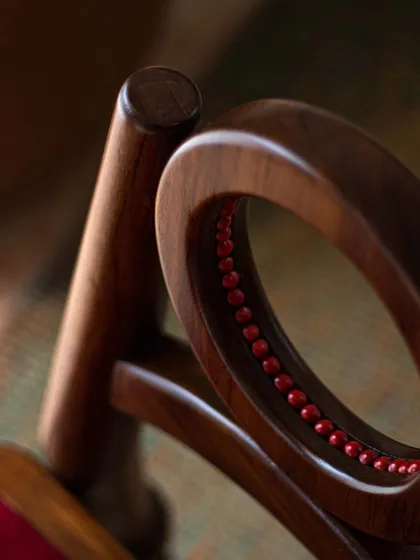 A series of images detailing the Manjadi chair, from its hand-turned legs inspired by the seed pod to the vibrant red upholstery. These shots highlight the craftsmanship and the deep cultural narrative behind this unique design.