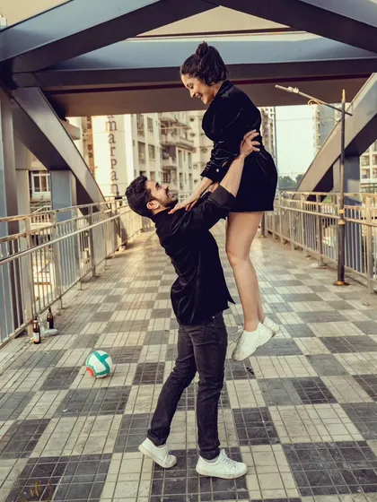 A joyful lift on a pedestrian bridge in Mumbai, capturing the urban energy and the couple's happiness. This dynamic shot is a great example of a fun, urban pre-wedding photo.