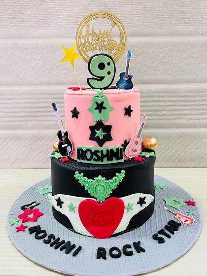 A two-tiered "Rockstar" cake for a 9th birthday, with pink and black layers, guitars, and stars.