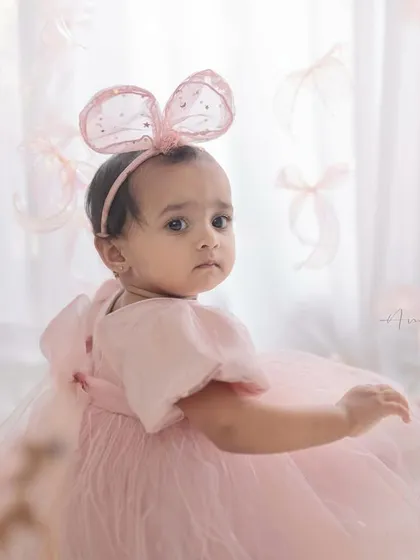 A sweet portrait of the birthday girl. The floating pink bows and matching headband add a touch of magic to this first birthday photo.