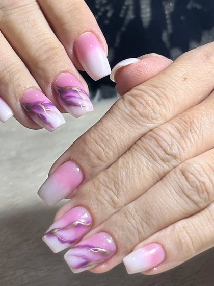 A beautiful combination of techniques. This design features a pink and white ombre base with purple marble accent nails, tied together with delicate gold lines.