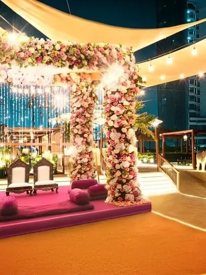 A stunning rooftop mandap setup, framed by pillars of beautiful pink and white flowers. This shows how our catering presentation integrates seamlessly with the main event decor to create a cohesive, beautiful space.