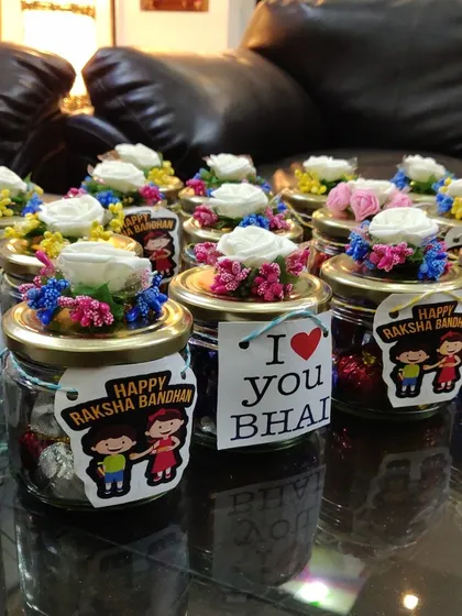 A bulk order of my mini Rakhi gift jars, each filled with assorted chocolates and decorated with a flower and a personalized tag.