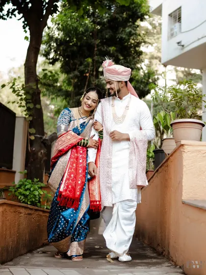 A beautiful shot of the couple walking together after their Marathi wedding ceremony. The bride's traditional blue Paithani saree and the groom's classic white kurta create a timeless look.
