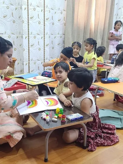 A teacher gives one-on-one guidance to our youngest campers during a rainbow painting session, ensuring they feel supported.