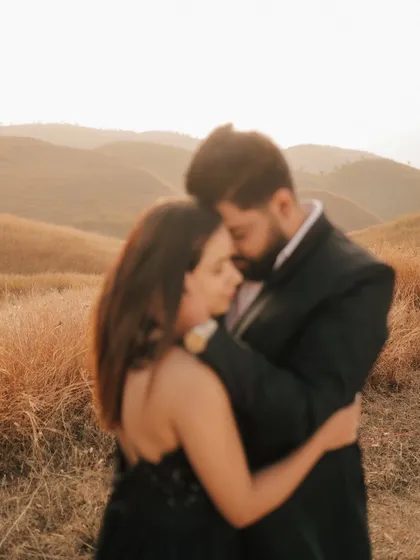 A soft-focus, artistic shot of the couple embracing in a field, creating a dreamy and romantic mood.