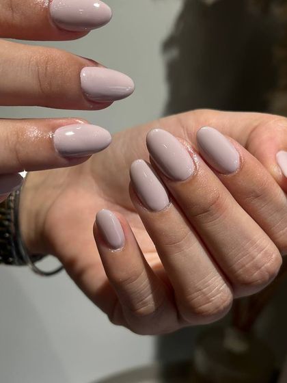 A soft, grey-toned nude polish on oval nails. This cool, sophisticated neutral is a modern and chic choice.