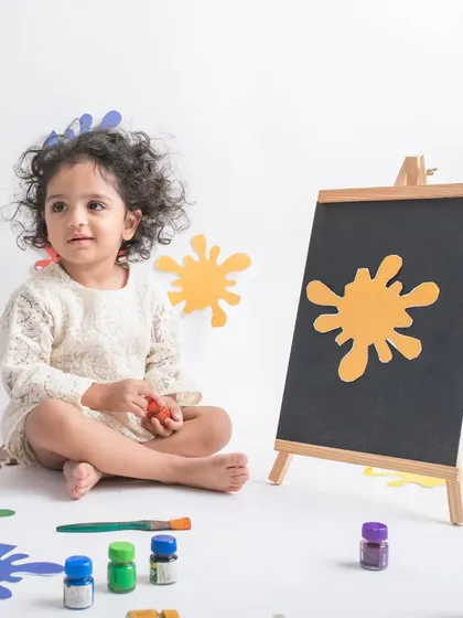 A little artist at work. This colorful paint-splatter theme is a fun and creative concept for a toddler photoshoot.